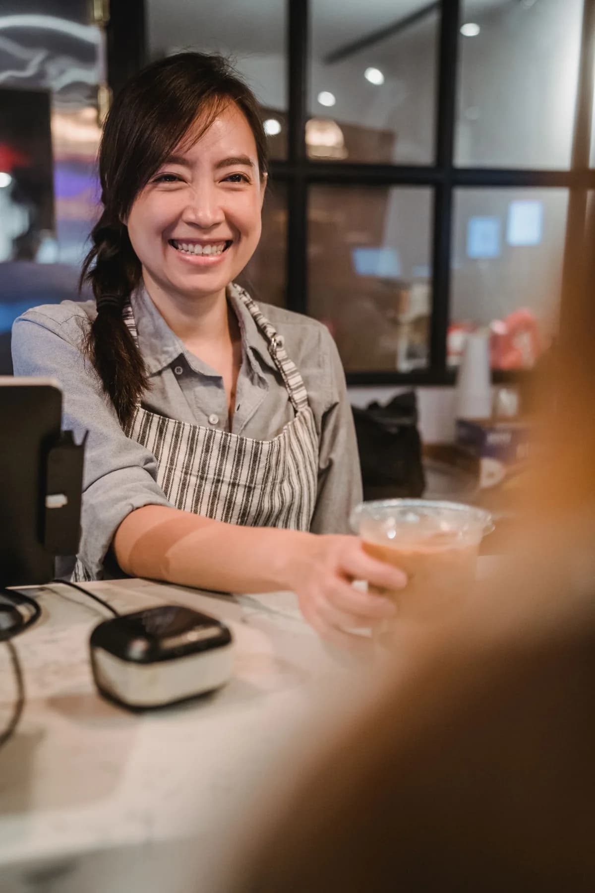 A barista serving iced coffee across a café counter
